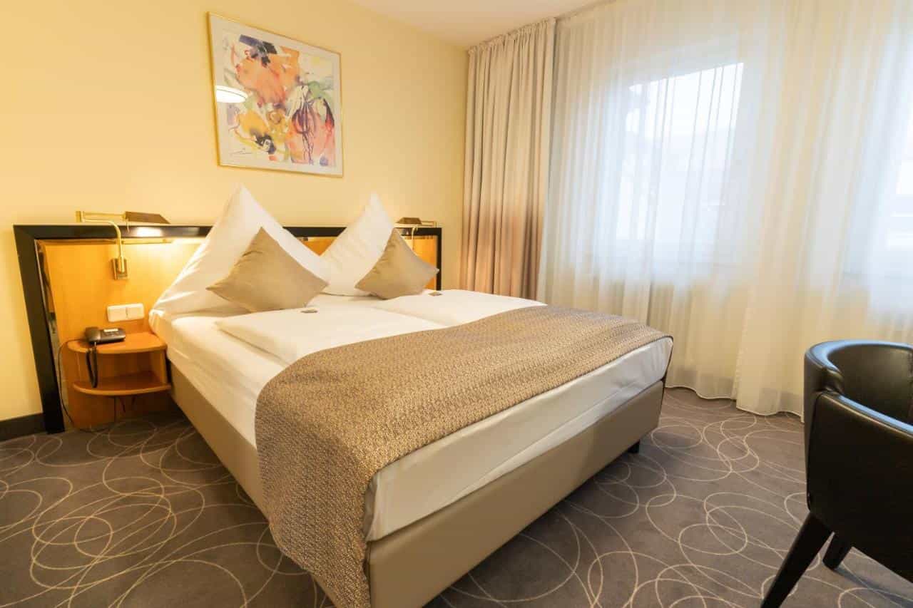 Hotel room at Hotel am Stadtgarten in Radolfzell-am-Bodensee with double bed and bright window.