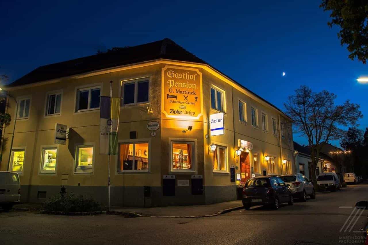 Gasthof Pension G. Martinek illuminated at night on a street in Baden bei Wien.