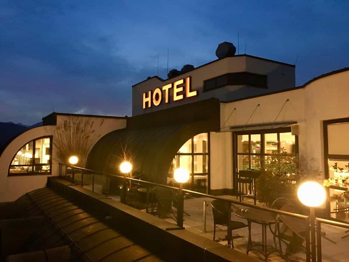 Illuminated "HOTEL" sign above terrace seating at dusk, Skycity Hotel Atrigon.