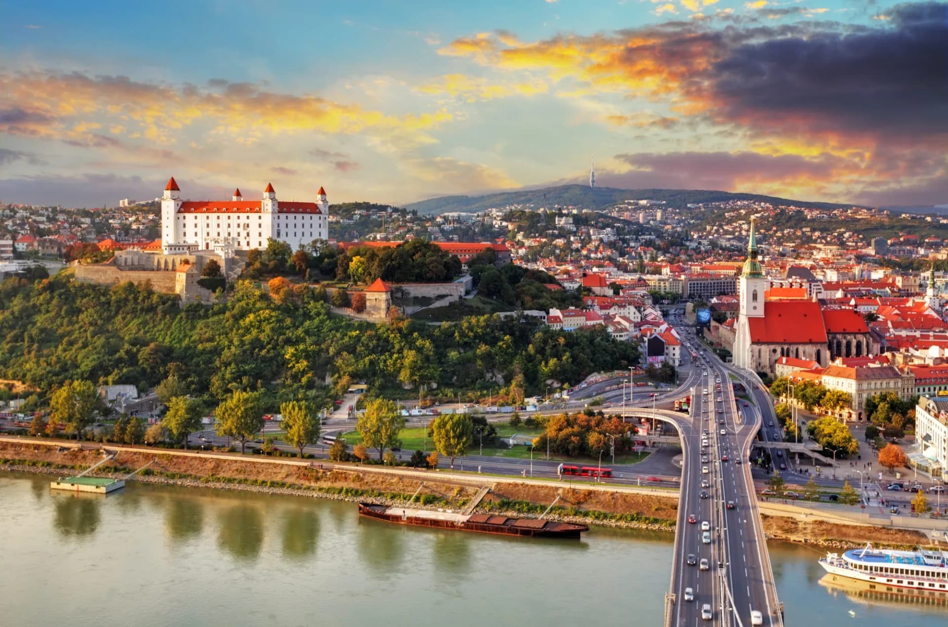 Bratislava Castle overlooking the city, river, and bridge at sunset.