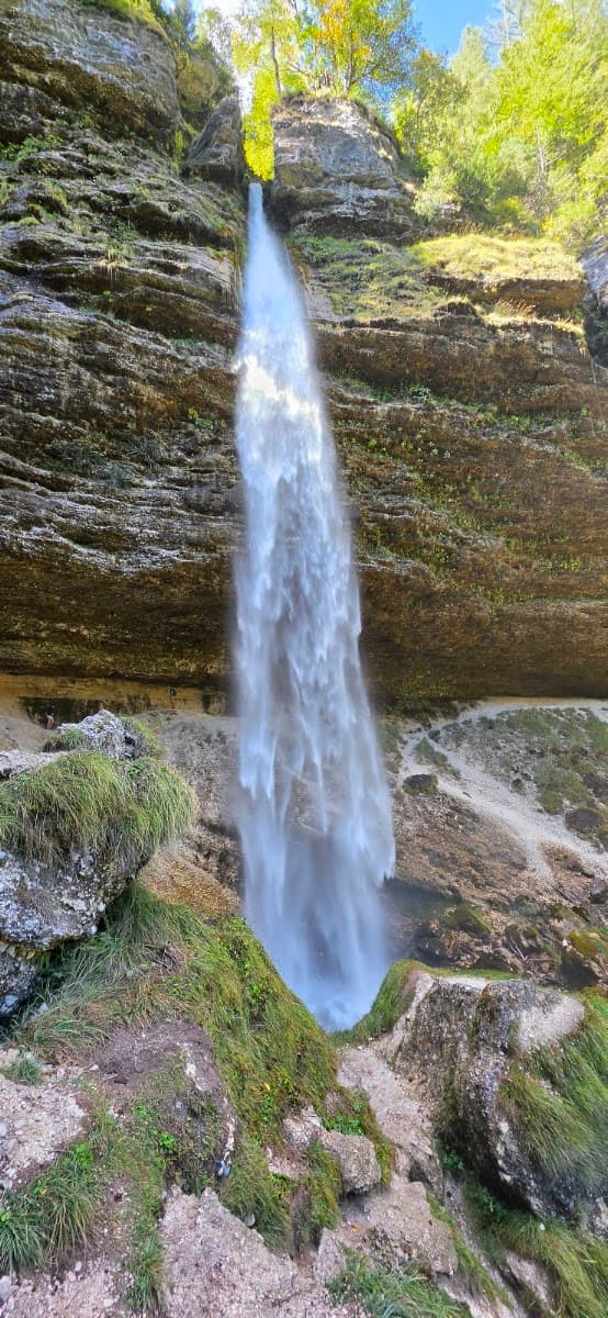 Tall waterfall cascading down rocky cliff face with lush green vegetation