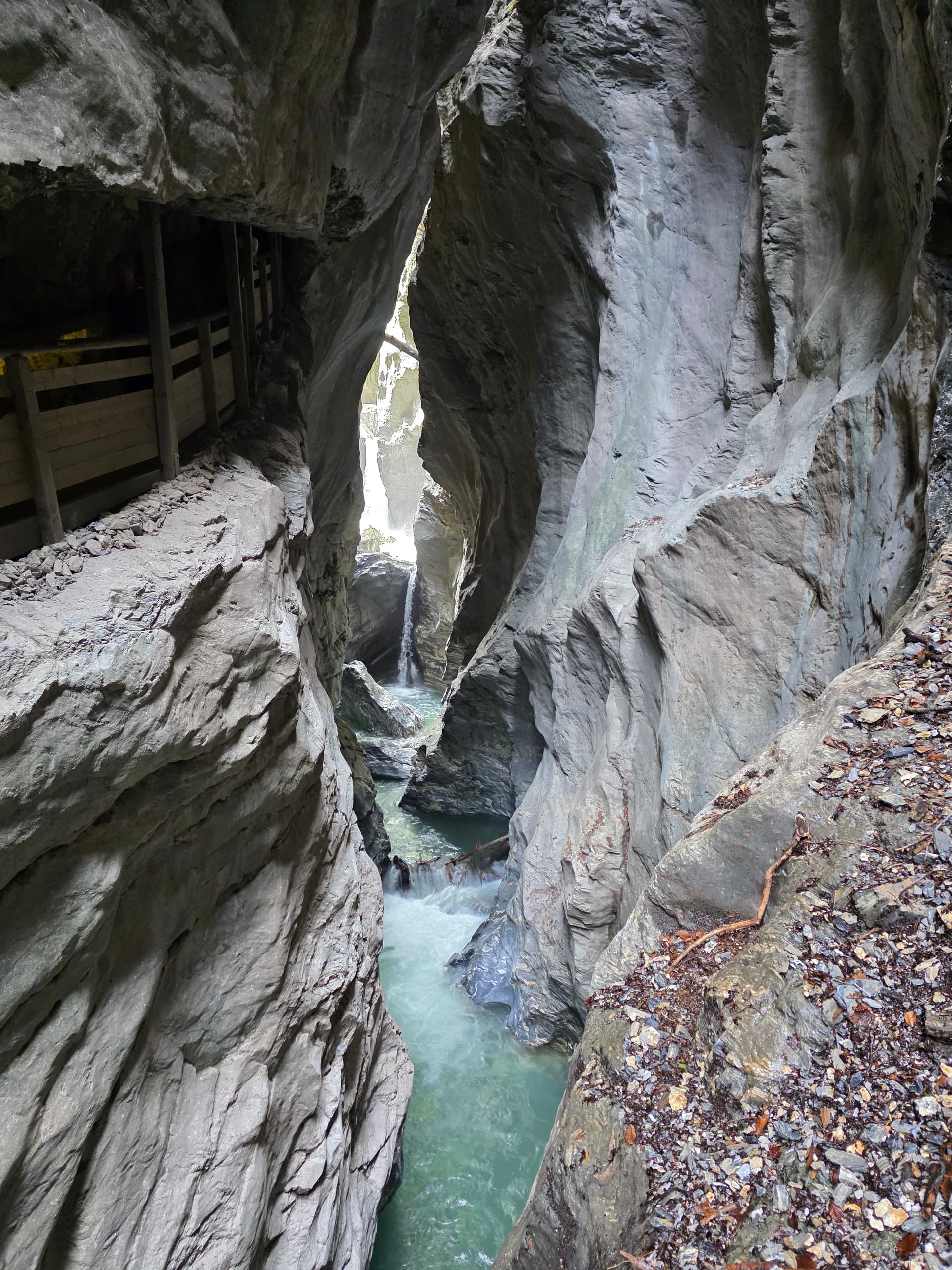Narrow alpine gorge with rocky walls and stream flowing through water