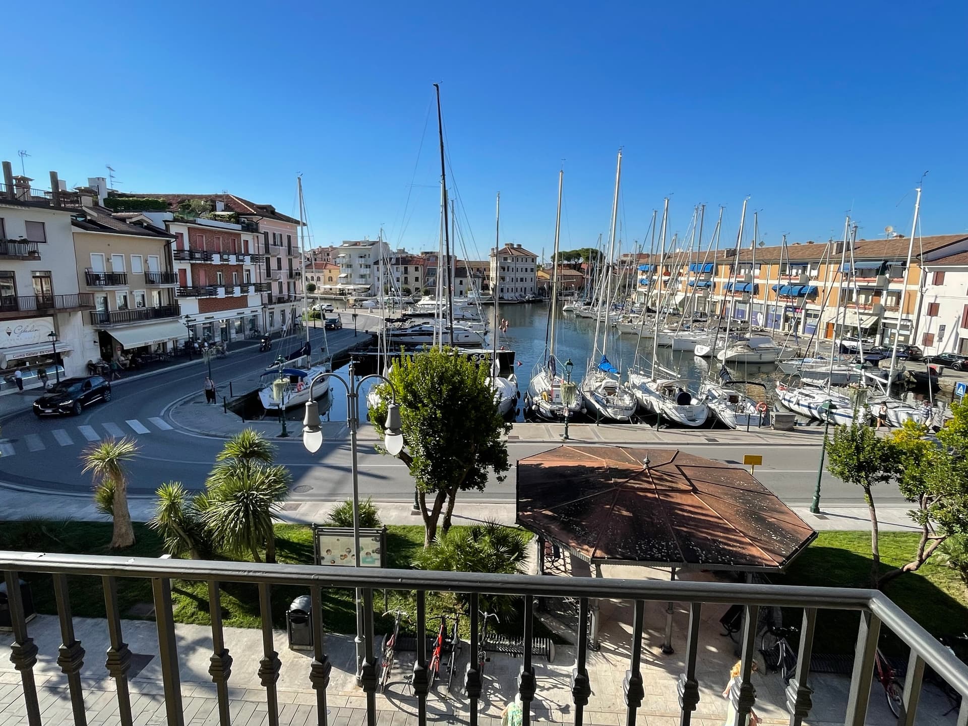 Grado harbor filled with sailboats and surrounded by buildings under clear blue sky