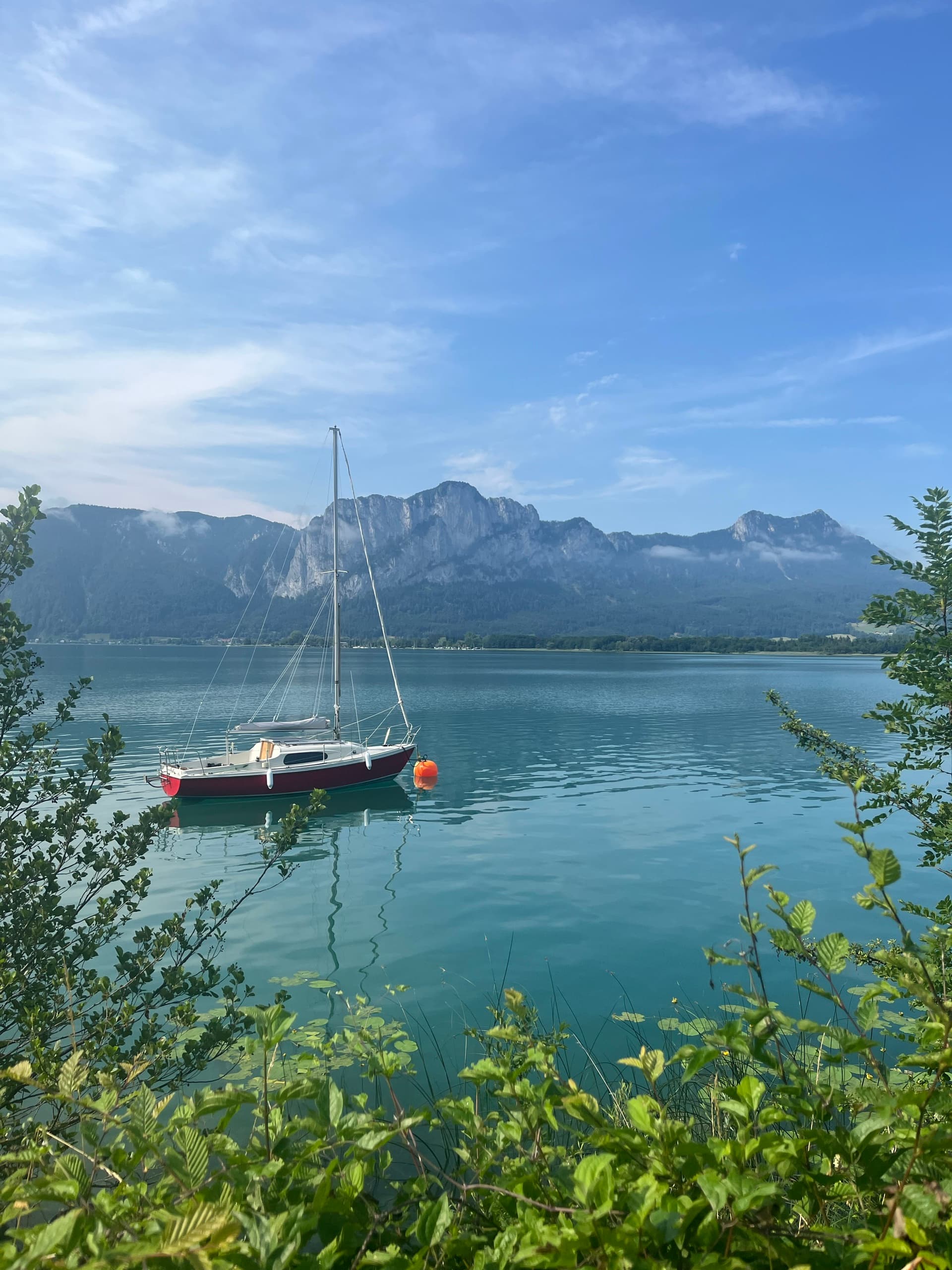 Sailboat on a turquoise alpine lake with mountains in the background