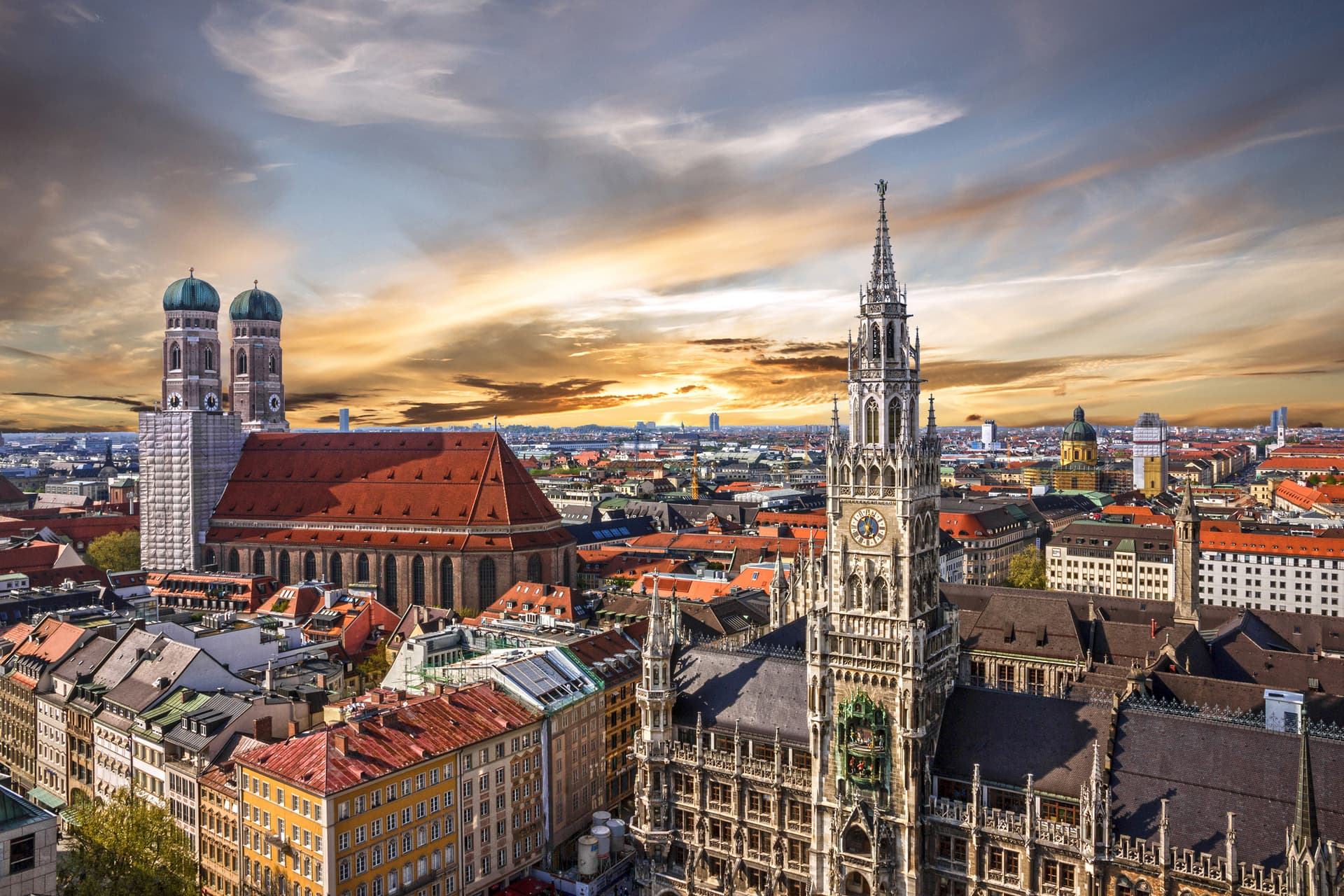 Munich cityscape with Neues Rathaus tower and Frauenkirche domes at sunset.