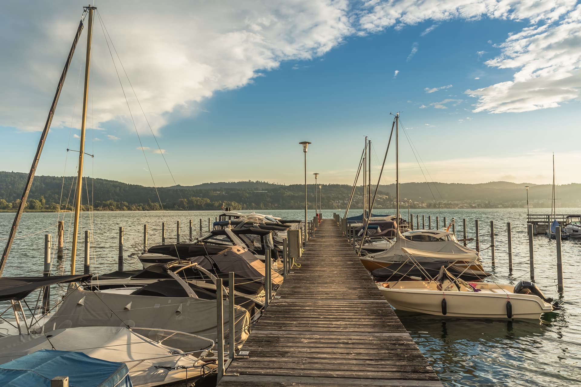 Wooden jetty with moored, covered boats in the marina on Lake Constance, Bodman-Ludwigshafen, Germany.