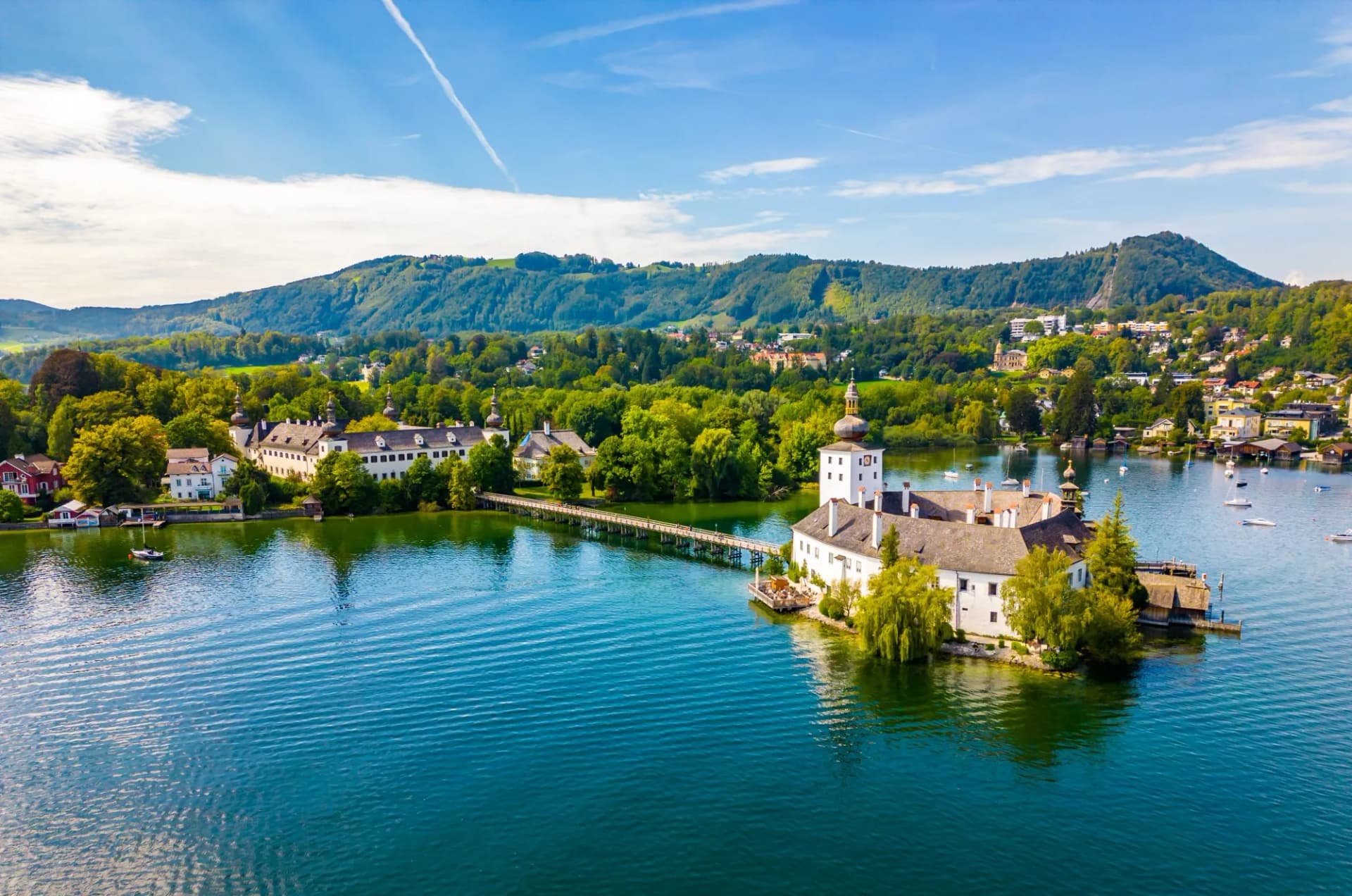 Schloss Ort on Traunsee lake in Gmunden, Austria, with forested hills in background.