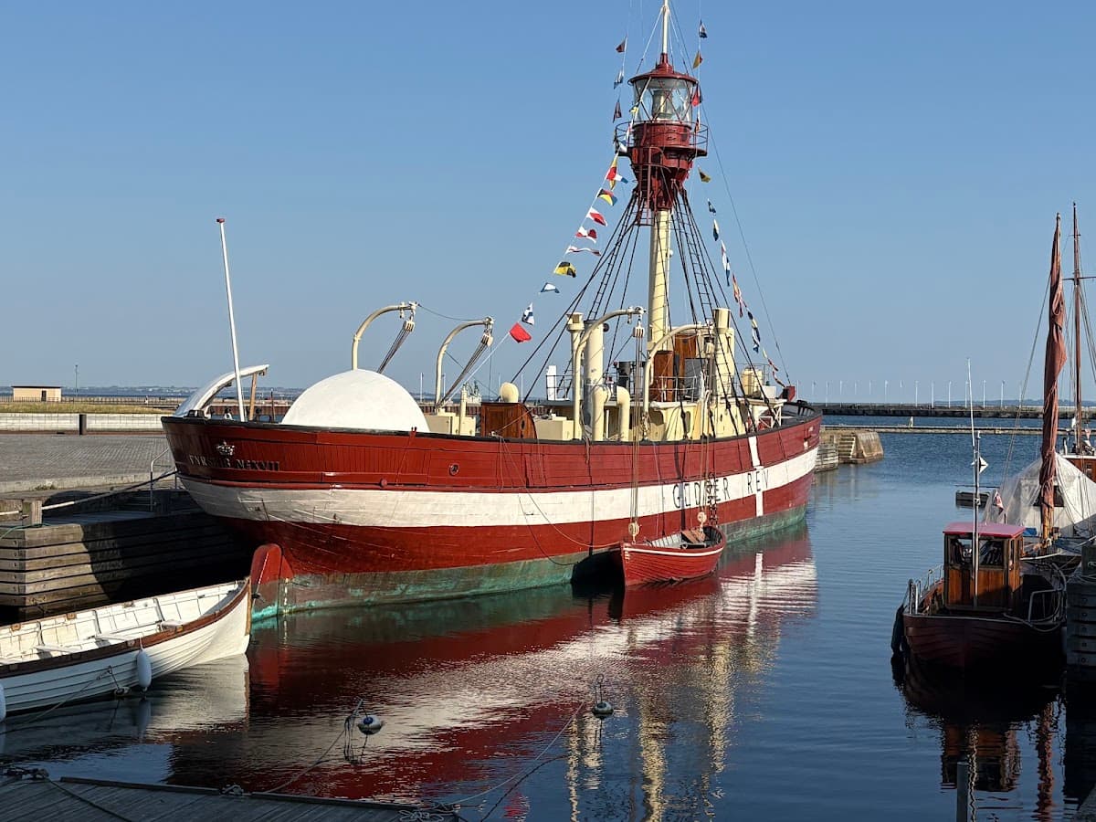 Red and white lightship moored in a harbor with small boats