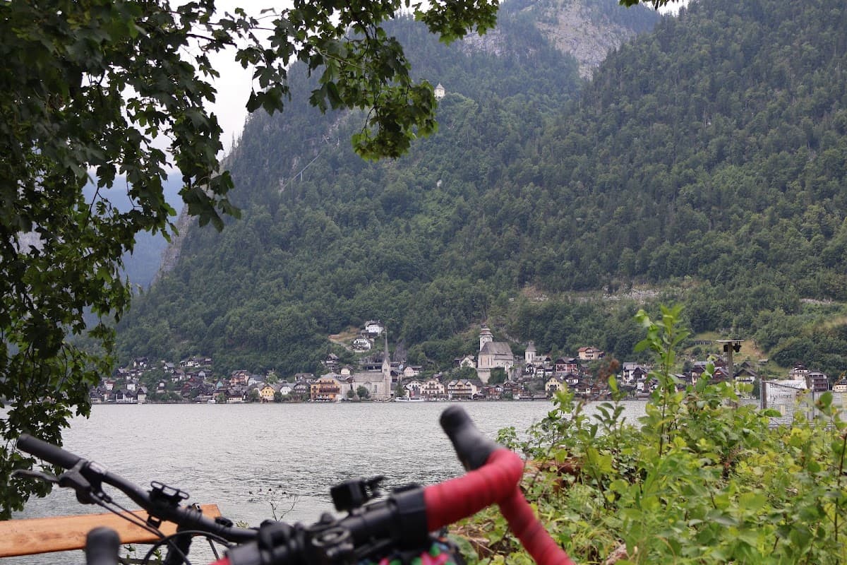 Bicycle handlebars overlooking a lakeside village with steep forested mountains